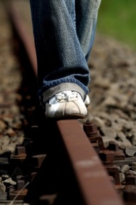 Gros plan sur les pieds d'un homme marchant sur des rails de train